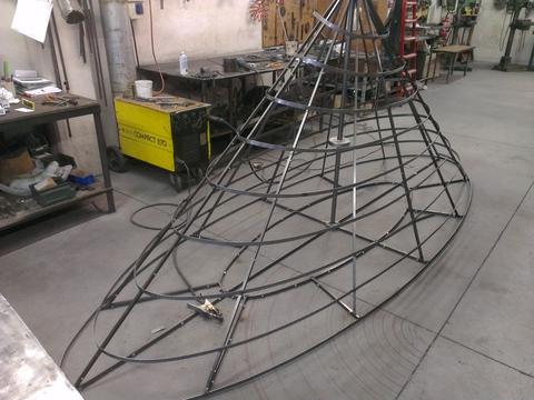 Metal framework of a large chandelier structure in a workshop.