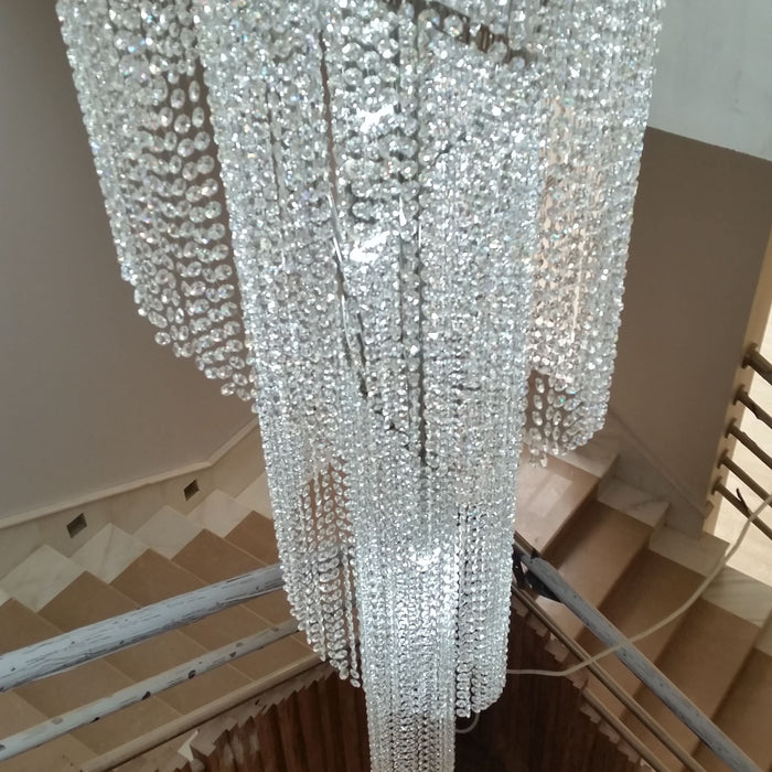 Tall crystal Twister-style staircase chandelier with matching crystal waterfall wall lights, installed in a client's foyer