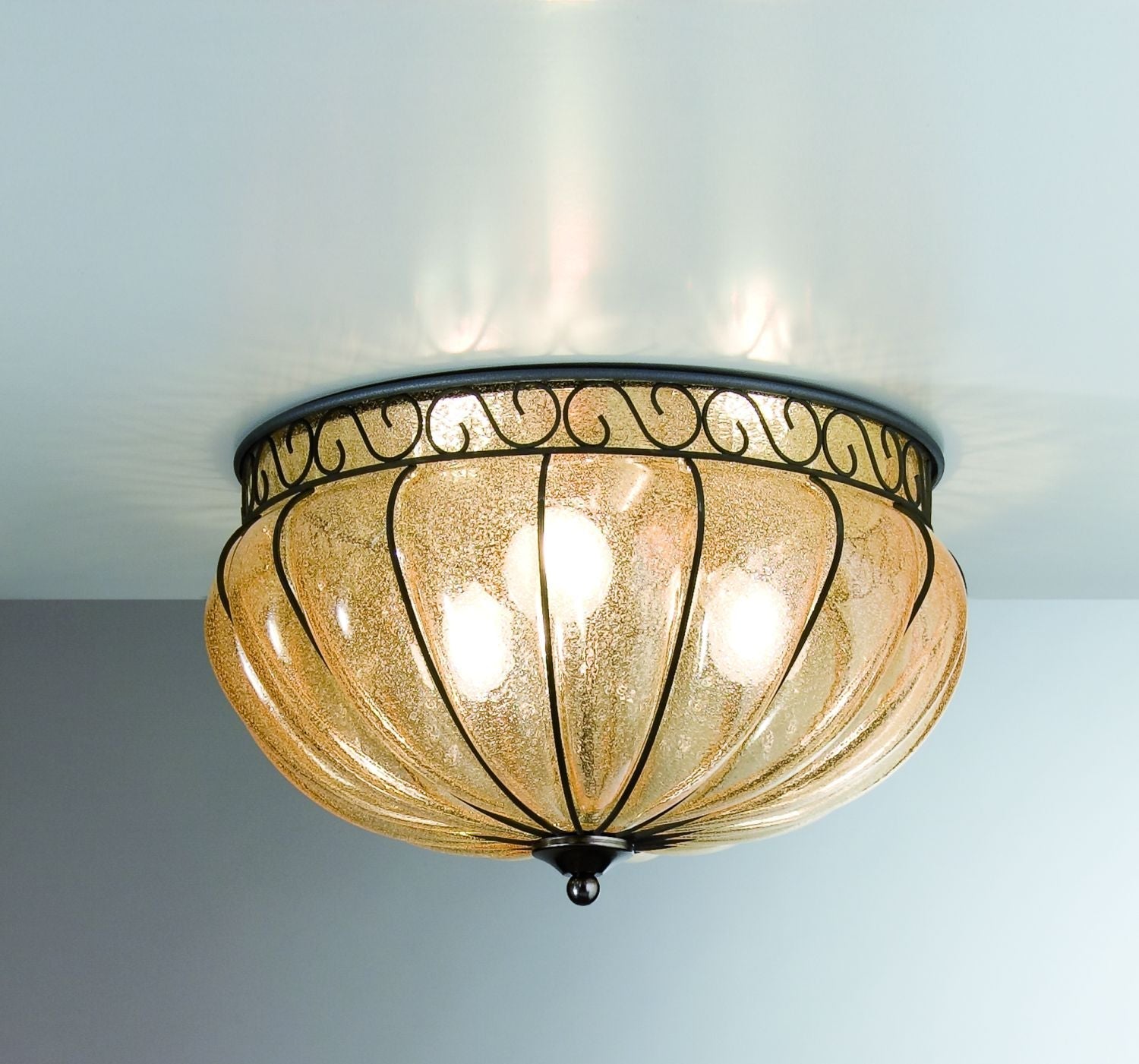 Classic amber hand-blown Venetian glass flush ceiling light with ornate bronze ironwork frame, installed on a hallway ceiling